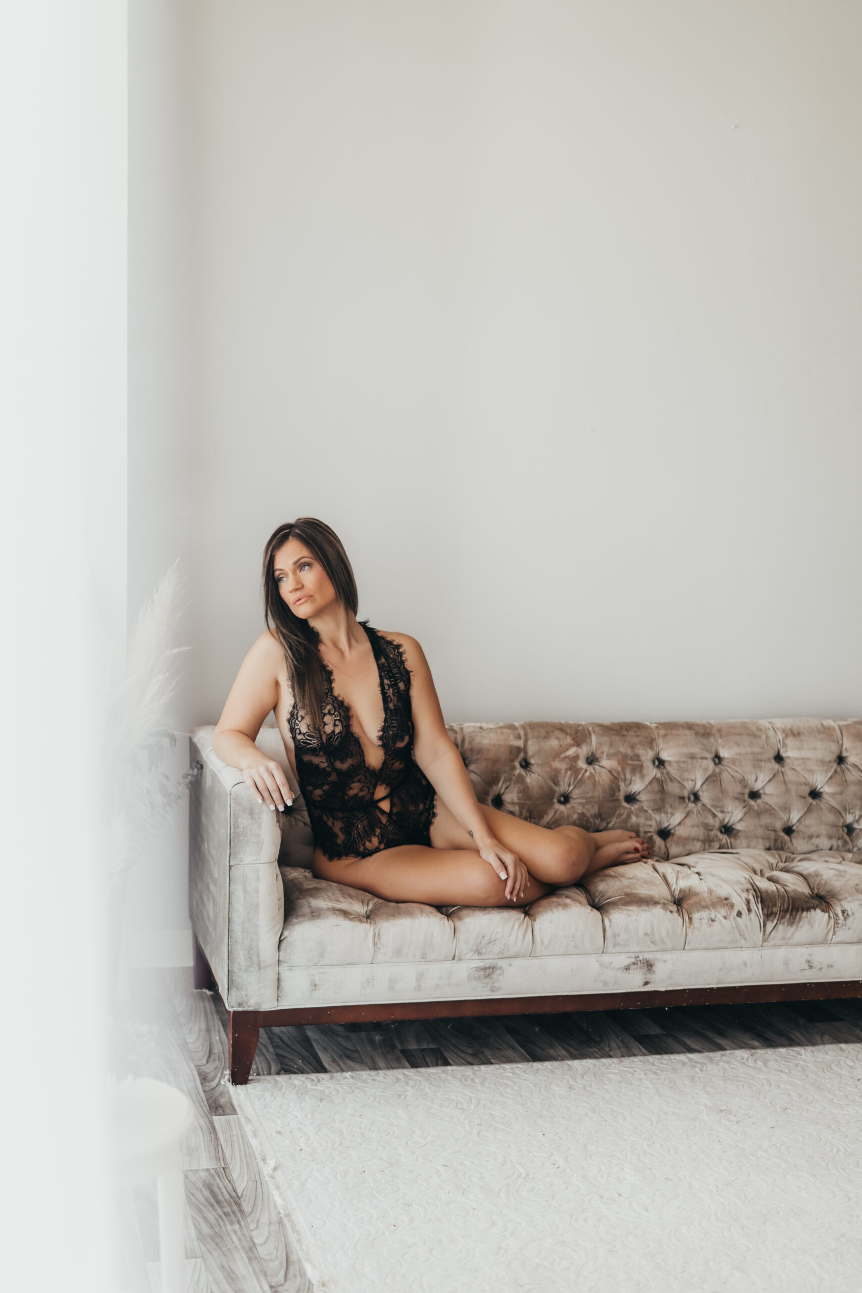 Beautiful woman poses on couch for her houston boudoir photography session with ally's photography