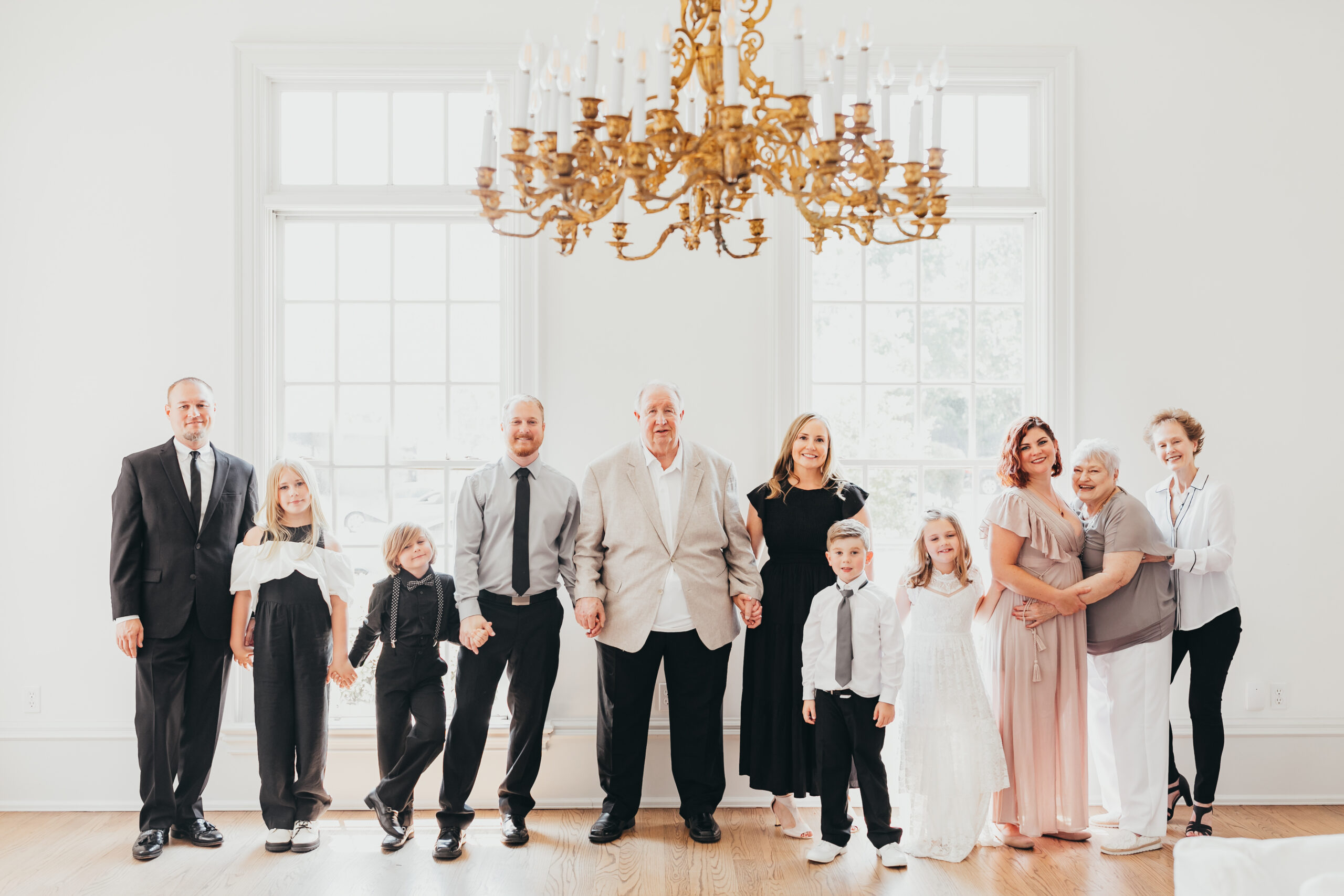 Extended family stands in a line for photographs by Ally's Photography