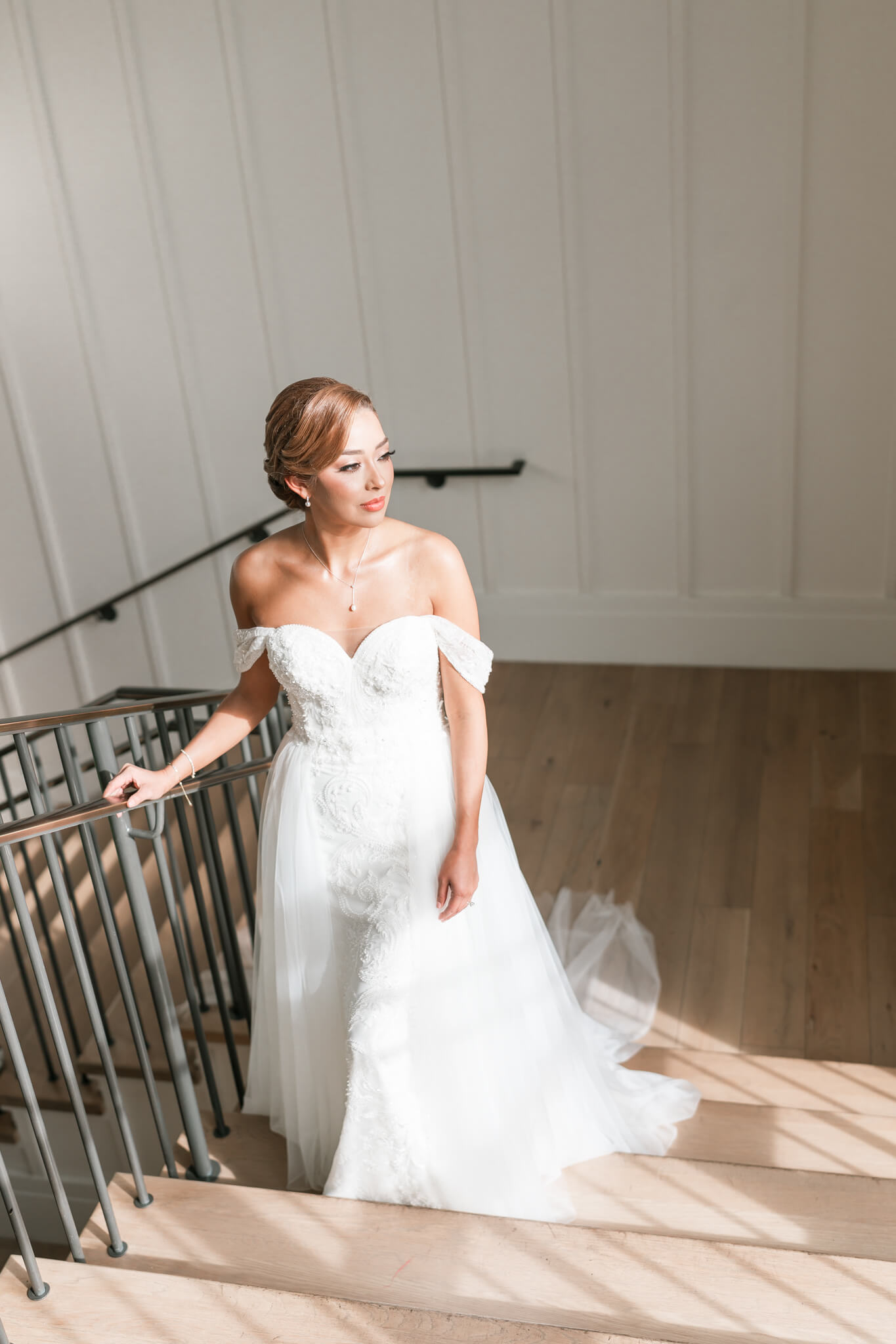 bride stands against beautiful staircase at one of Houston's best wedding venues.